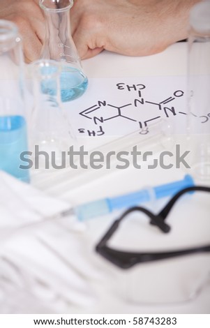 chemistry formula and flasks on the table - male hands in background