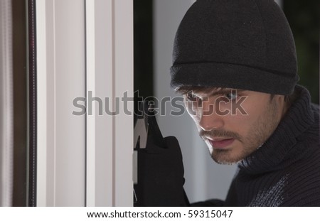 thief with crowbar breaking into a house by night