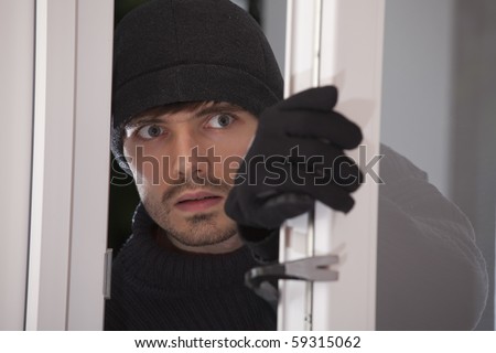 burglar with crowbar breaking into a house through glass door