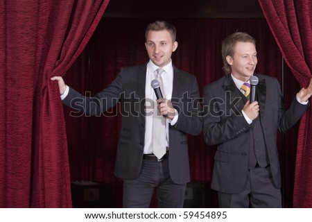 two comedian actors with microphones on stage
