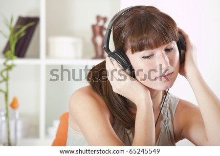 Woman sitting on the sofa and hearing music in earphones