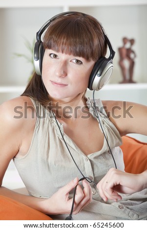 casual woman hearing music at home in earphones
