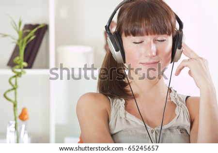 young woman hearing music in earphones at home