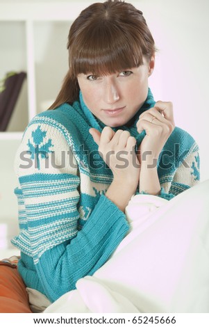 young woman in knit sweater sitting on sofa at home