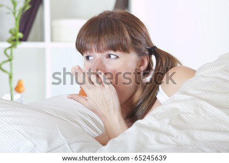 young woman awaking and yawning in bed