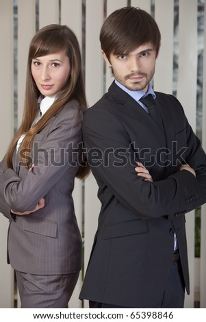 man and woman in business suits posing back on back