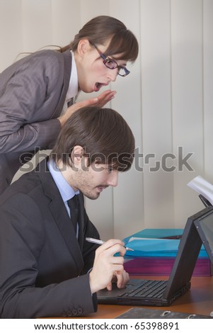 office scene - astounded woman looking over man shoulder at his computer