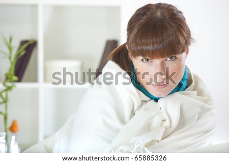 recreation at home - portrait of young woman covering with rug on sofa