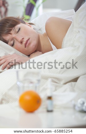 ill woman sleeping in bed - medicine on table in foreground