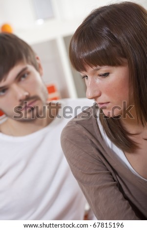 couple with problems - sad man and woman sitting on sofa