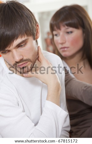 unhappy couple - frustrated man and sad woman at home
