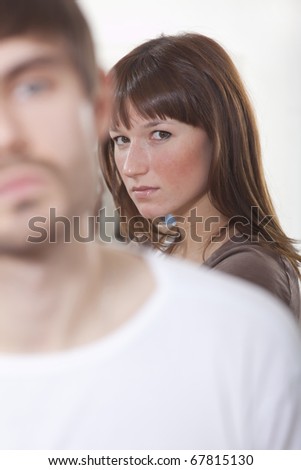 unhappy couple - sad woman in background and frustrated man in foreground