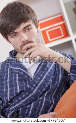 sad man in bathrobe sitting on sofa and thinking