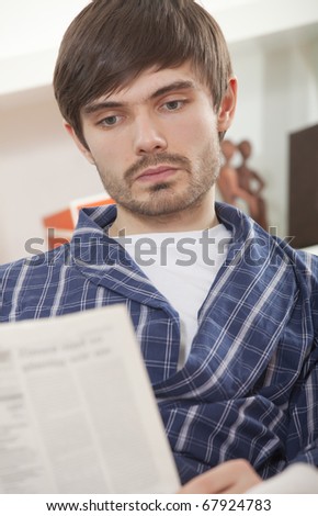 man in bathrobe reading newspaper at morning