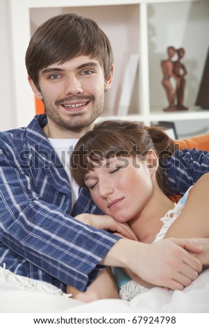 couple in bed - happy man hugging sleeping woman