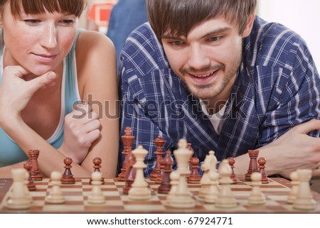 recreation at home - man and woman playing chess game on sofa