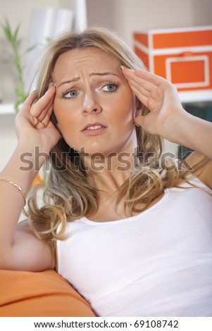 blond woman with headache massaging her head with both hands