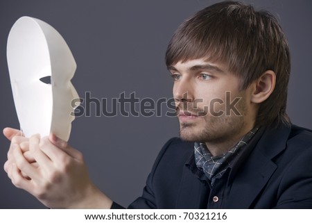businessman holding white theater mask in his hands