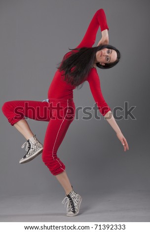 dancing woman in red sport suit over grey background