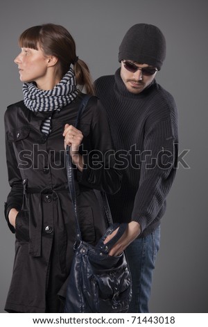 man pulls wallet out of a woman handbag