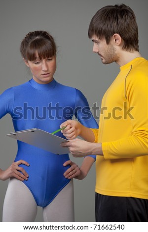 personal trainer giving instructions young woman in blue leotard