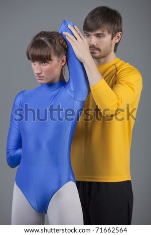 personal trainer helping woman in leotard with workout