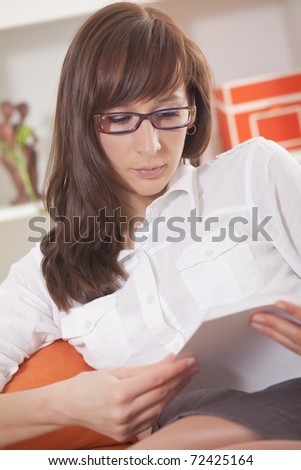 woman in glasses and white business shirt reading book at home
