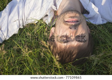 man in linen shirt relaxing in field