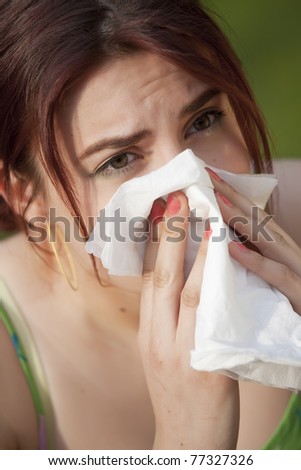 young woman with pollen allergy sneezing in handkerchief