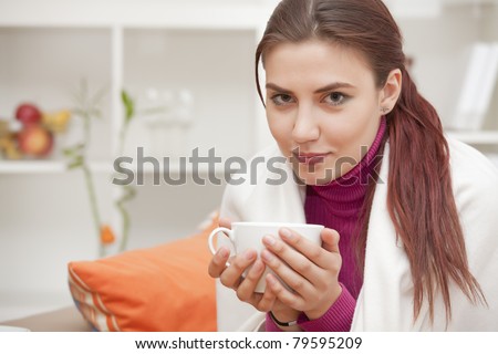 relaxed young woman at home with cup tea in her hands