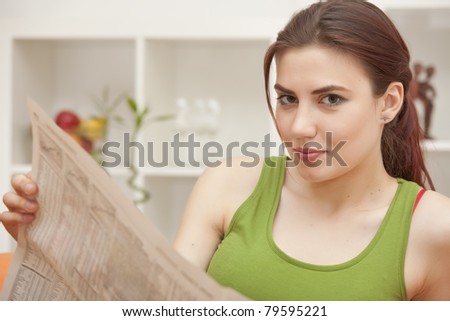 young woman holding newspaper sitting on sofa
