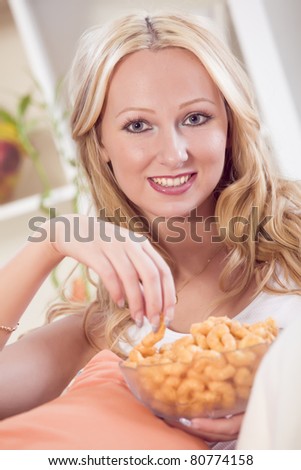 relaxing woman eating chips while sitting on sofa