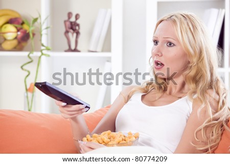 shocked woman with remote control watching television