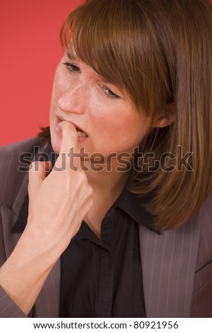 stressed woman biting her nails over red background