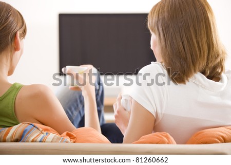 two women sitting in front of monitor watching television