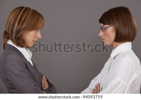 Two female business rivals in conflict over grey background