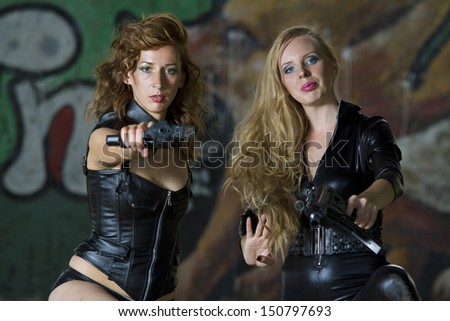 Two leather clad gun women aiming in the camera