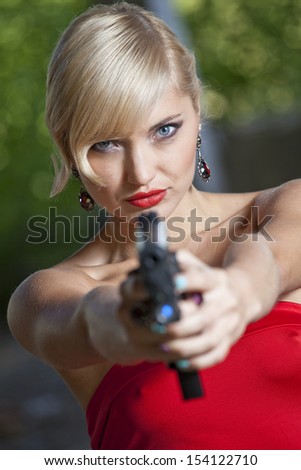 Woman in retro look pointing a gun at the camera