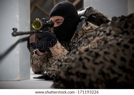 Sniper - soldier in camouflage and balaclava aiming with a sniper rifle