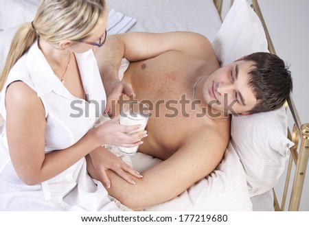 Woman in white coat caring sick man with a milk