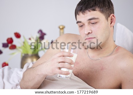 Sick and unhappy man with glass milk on bed