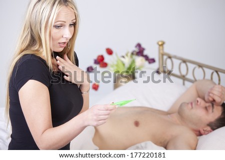 Ill man in bed and worried woman sitting on bed