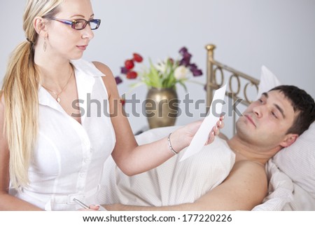 Woman reading medical report in front of sick man on the bed