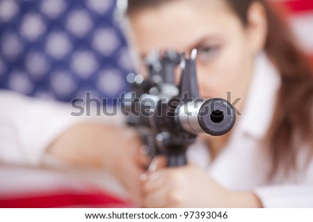 woman aiming with machine gun over american flag - focus on gun barrel