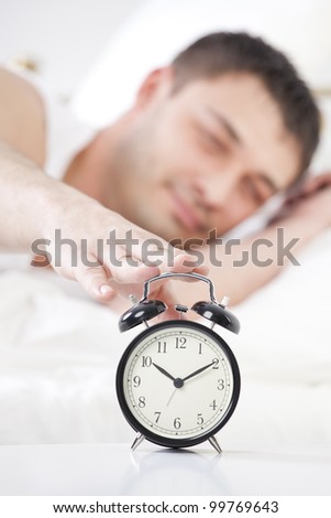Sleeping man reaching for ringing alarm clock