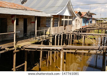 Houses on stilts rise above the polluted water in Islandia Peru