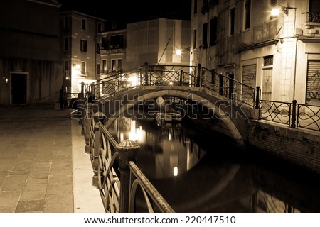 Venice canal late at night with street light illuminating bridge and houses