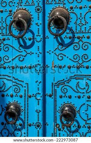 A blue door with black studs and stone ornament at doorway in Tunisia