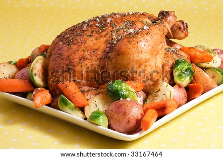 Roasted chicken seasoned with herbs and garnished with potatoes, carrots, and brussell sprouts.