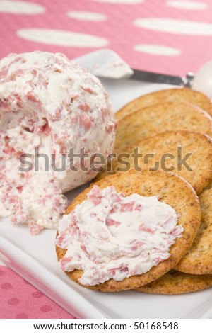 Cheese ball made with cream cheese, chipped beef, and horseradish, spread on a wheat cracker.